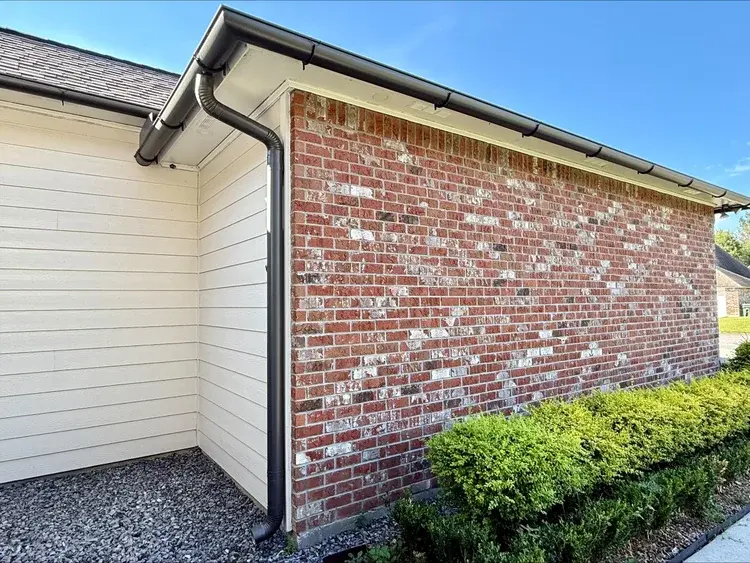 Fresh seamless gutter and downspout installed on a brick home