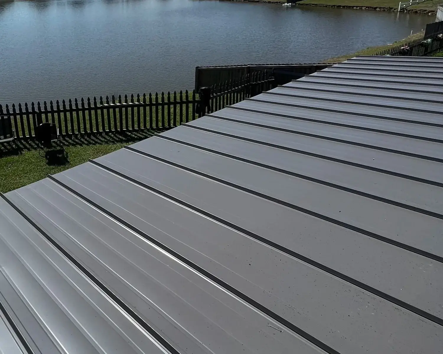 Low-angle view of a standing-seam metal roof beside a lake