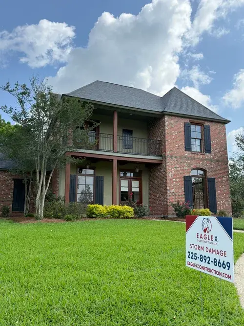 EagleX 'Storm Damage' yard sign in front of a two-story brick home
